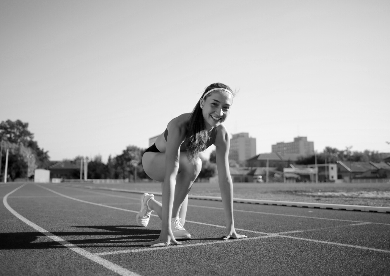 Woman in Red Tank Top and Black Shorts Running on Track Field